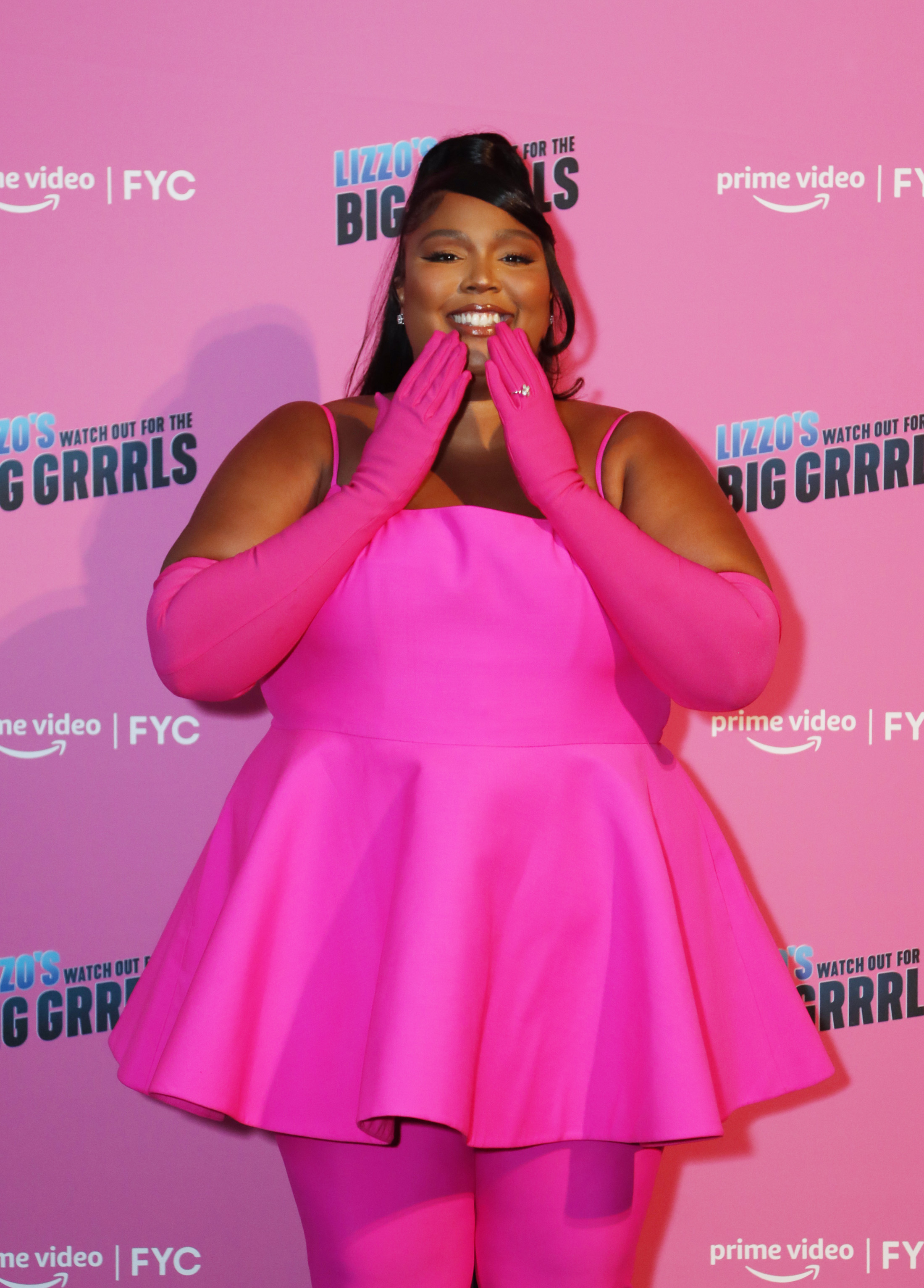 At the Watch Out for the Big Grrrls FYC event in June 2022, Lizzo wore a bright hot pink peplum top with matching leggings and gloves, showcasing her fuller figure and visibly rounder midsection.