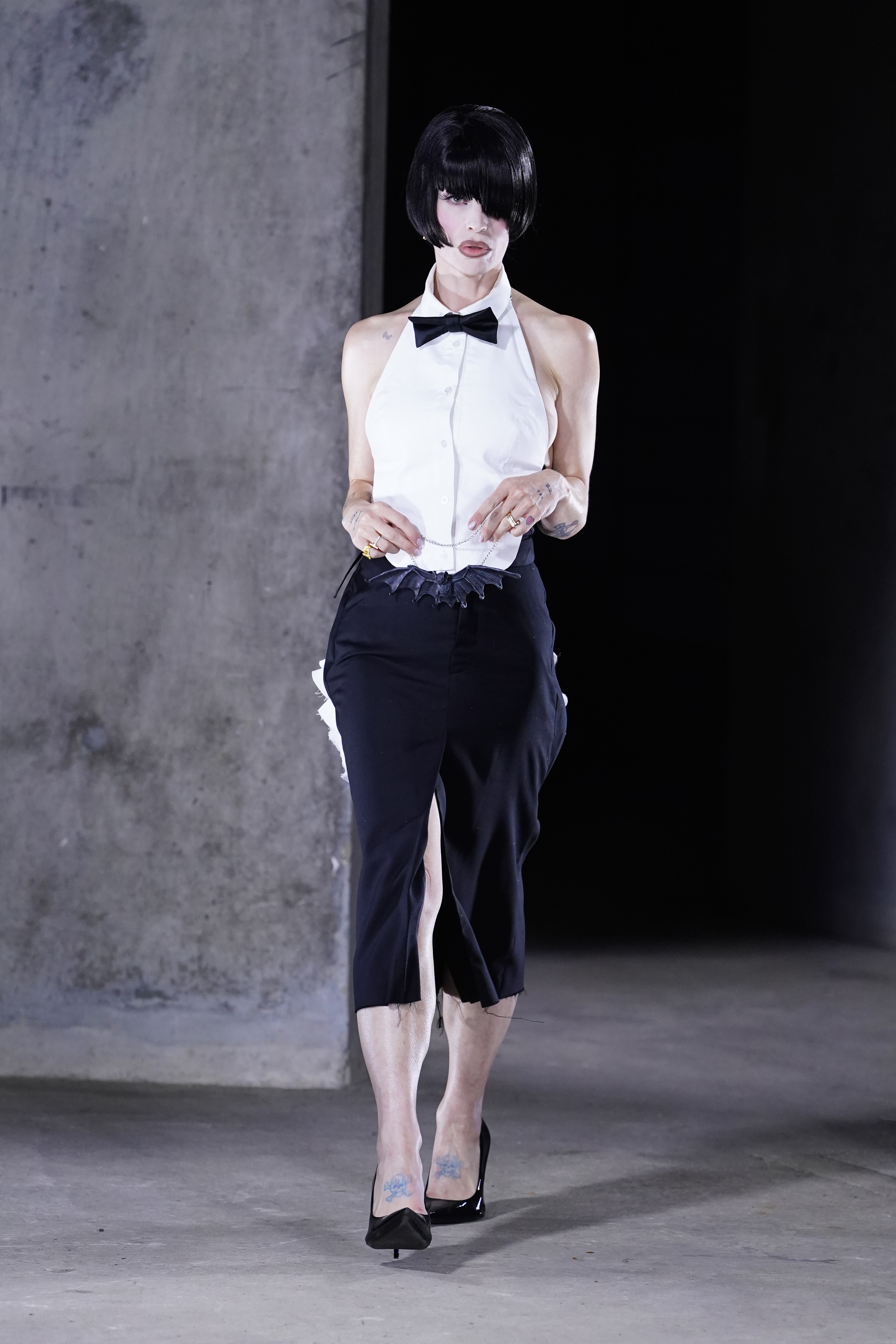 Kelly Osbourne walks through Collins Music Hall in London in a white halter-style shirt, black bow tie, cropped black bottoms, and pointed heels during Natasha Zinko's show on September 18, 2026. | Source: Getty Images