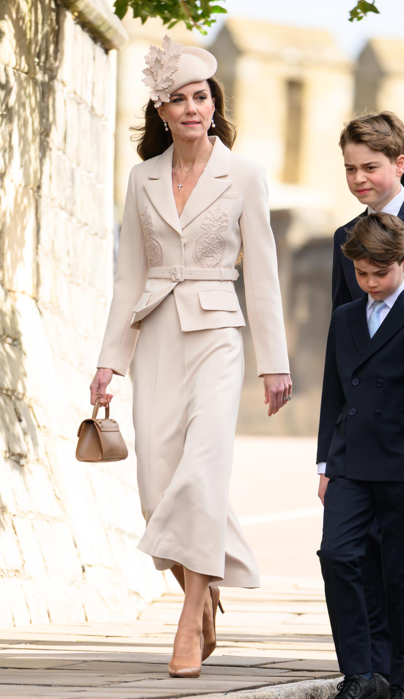 A purposeful stride along the Windsor Castle grounds, and arguably the clearest view of the Princess of Wales's full monochromatic look from collar to heel. The structured lace appliqué blazer and the Ralph Lauren pumps all come together in one unbroken sweep of cream. Prince George trails just behind her to the right, and even at this angle and distance, the height comparison speaks entirely for itself. | Source: Getty Images