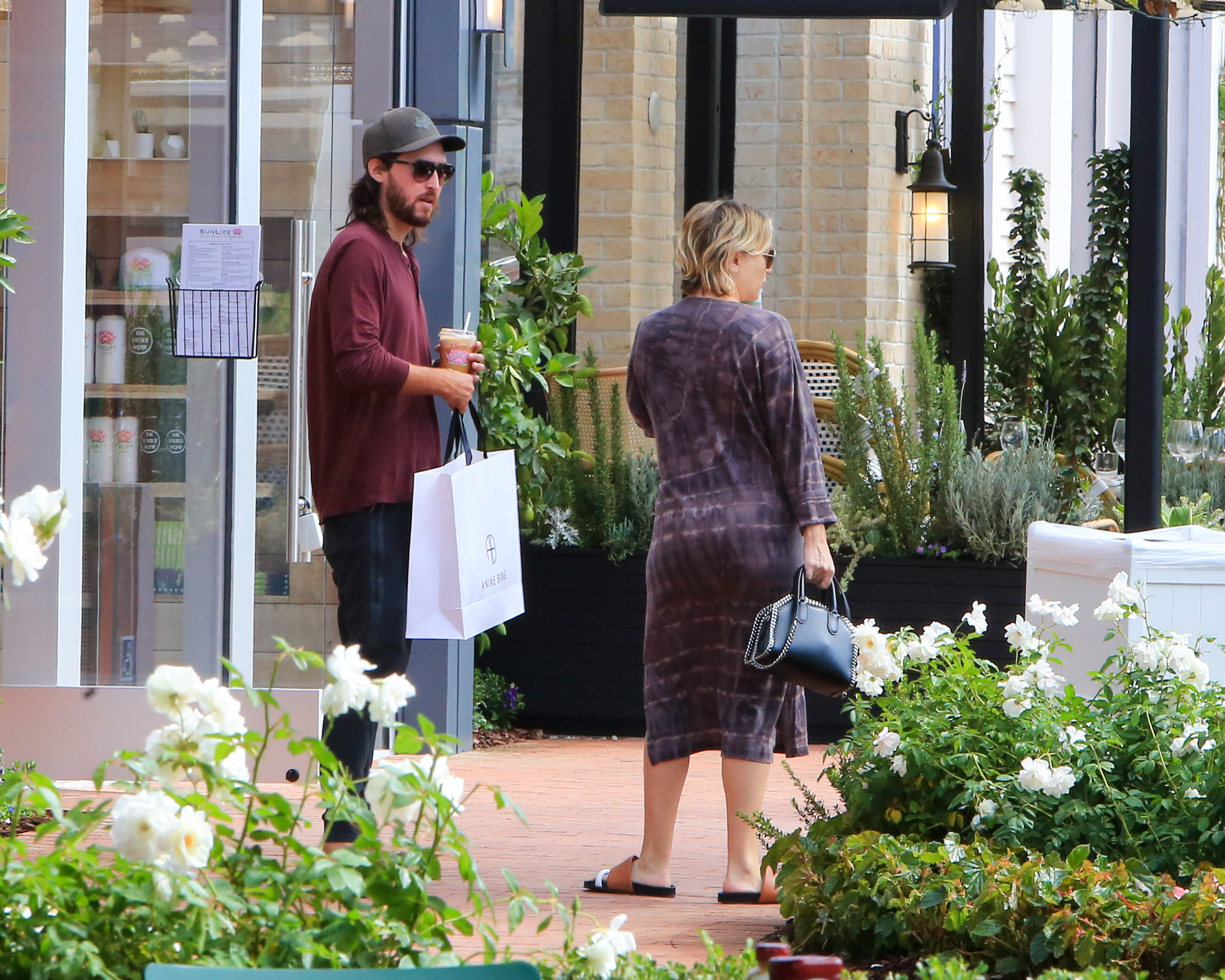 Danny Fujikawa and Kate Hudson were spotted enjoying a relaxed day out. Danny held a shopping bag and an iced drink while Kate, dressed in a casual tie-dye dress and sandals, strolled beside him carrying a chic black handbag.