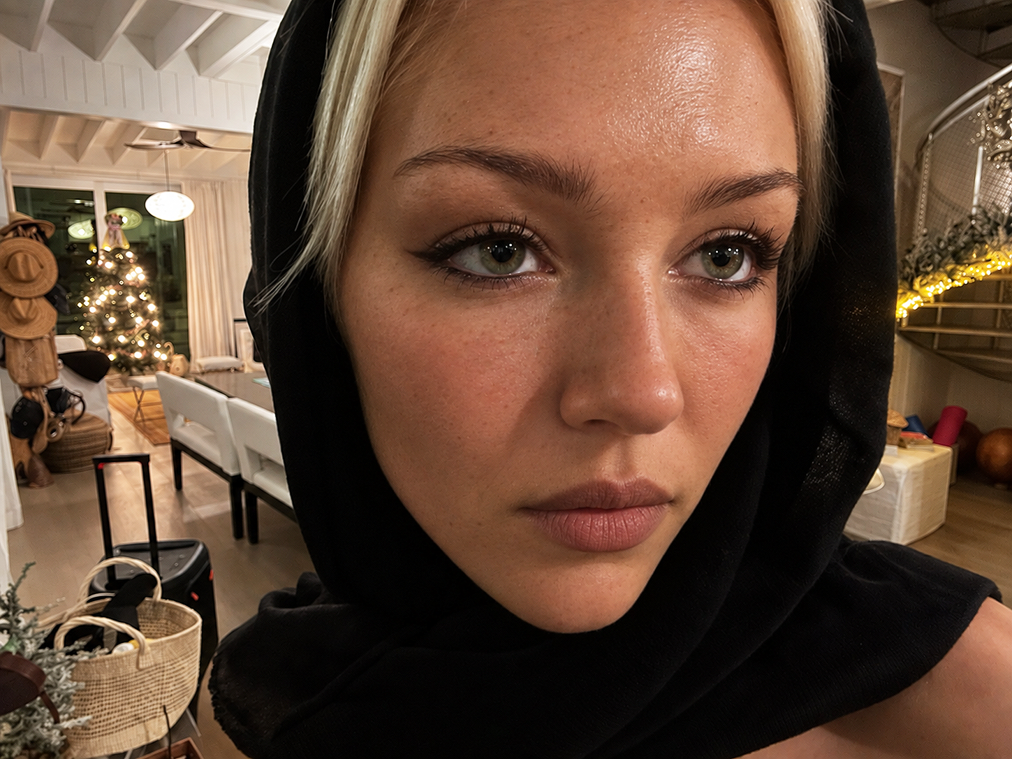 In another AI depiction, Delilah Belle Hamlin appears in a black hood, with face-framing blonde strands, lightly freckled skin, and softly shaped features. | Source: ChatGPT