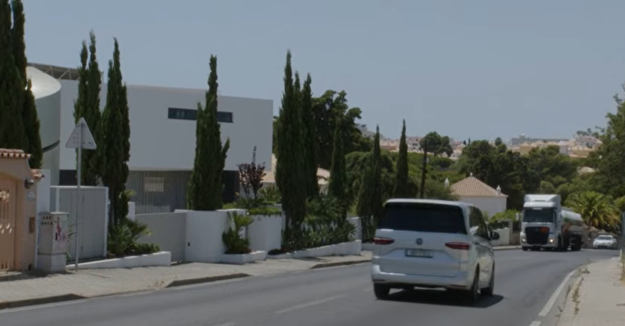 Traffic passes along the quiet road outside Bonnie Tyler’s Portugal home, where the sleek white property sits among towering cypress trees and lush greenery. | Source: YouTube/AFP News Agency