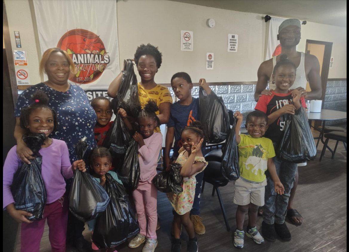 A group photo of Shamar Elkins, Shaneiqua Elkins, and their children shows them gathered indoors, smiling and holding bags together. | Source: Facebook/Shaneiqua Elkins