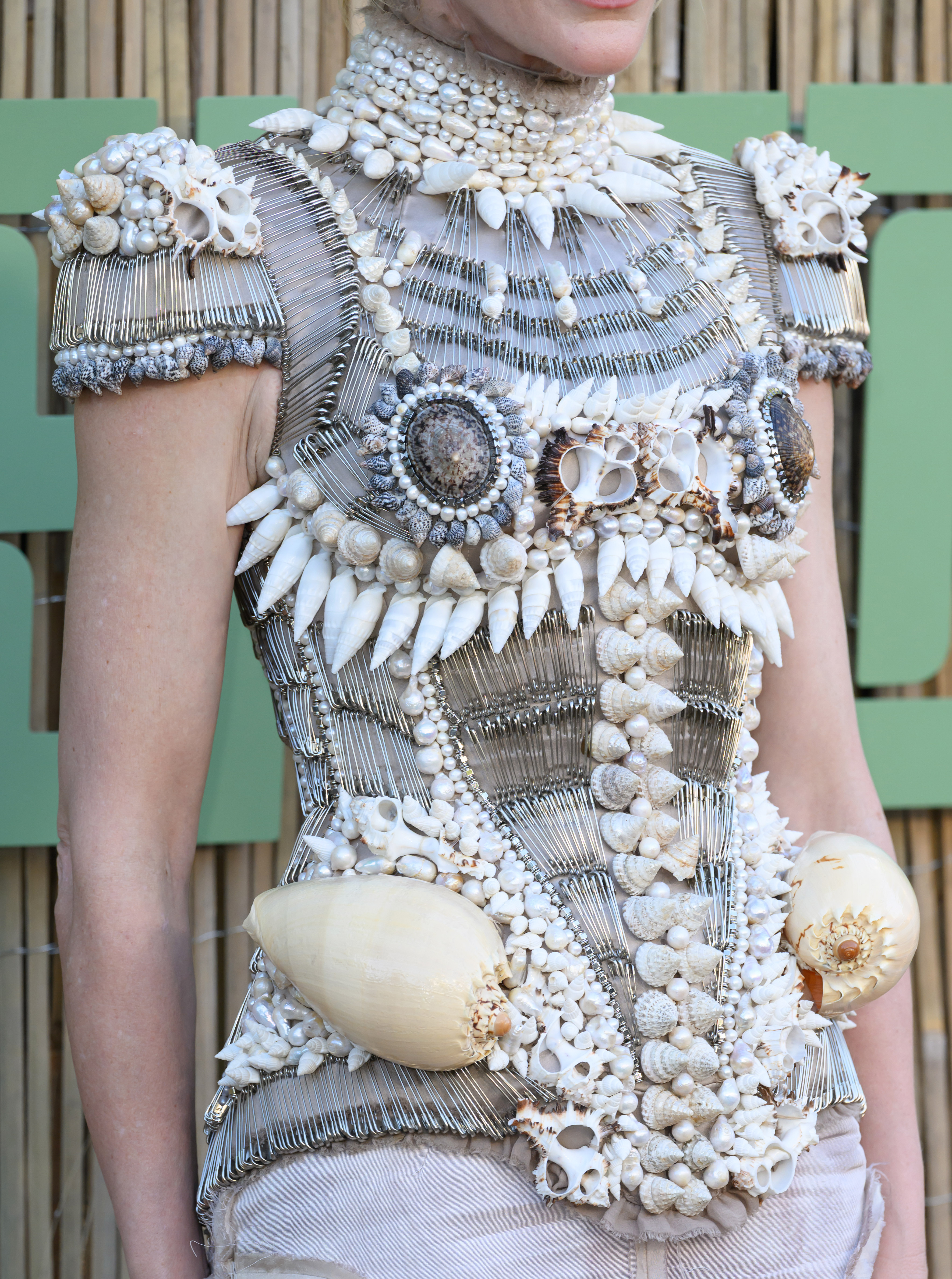 Two large spiral shells were placed prominently at the hips, while smaller shells and pearls lined the chest and collar, adding dimension and texture.