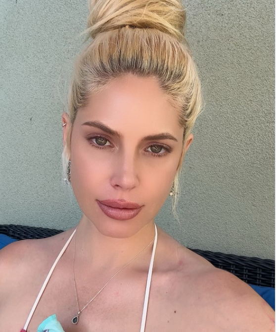 A polished summer selfie highlighted Cleo Rose Elliott’s sun-kissed features in an Instagram update from July 19, 2026. Looking straight into the camera, she swept her blonde locks into a voluminous top knot, accenting bare shoulders in a white halter neck top with a delicate pendant necklace and soft neutral glam. | Source: Instagram/cleoroseelliott