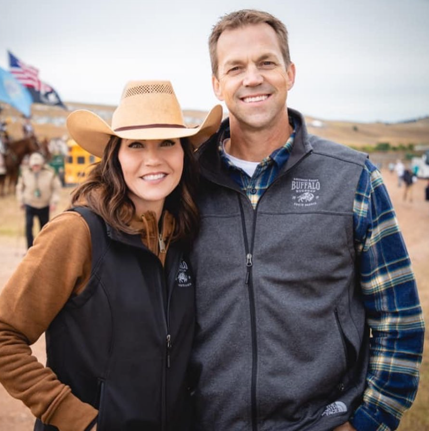 Dressed in casual outdoor wear, Kristi and Bryon stand close in a rural setting—easy smiles and practical attire capturing a grounded, everyday side of their life together. | Source: Instagram/sdbryonnoem