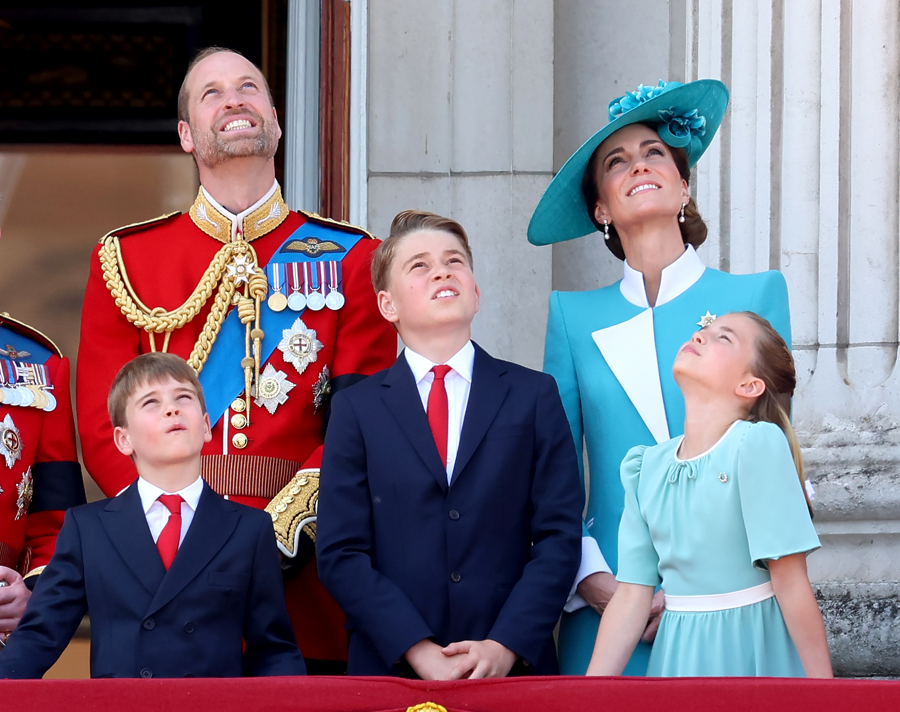 Prince William, Prince George, Princess Charlotte, and Princess Catherine look up at the sky as they watch the RAF flypast from the Buckingham Palace balcony.