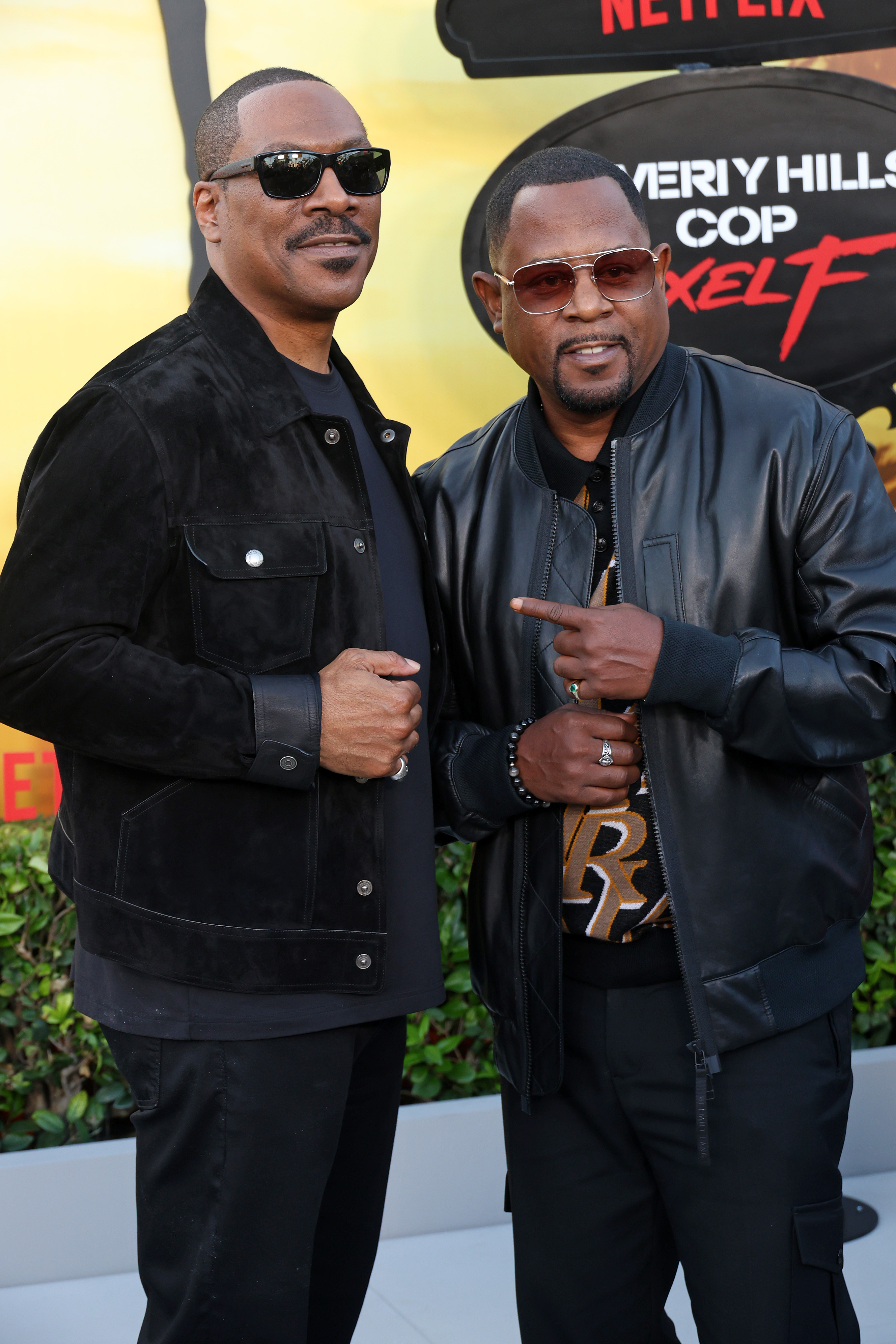 Martin Lawrence poses alongside Eddie Murphy at the same premiere, both dressed in dark, stylish outfits. Standing shoulder to shoulder, Martin gestures toward Eddie, highlighting their camaraderie on the red carpet.