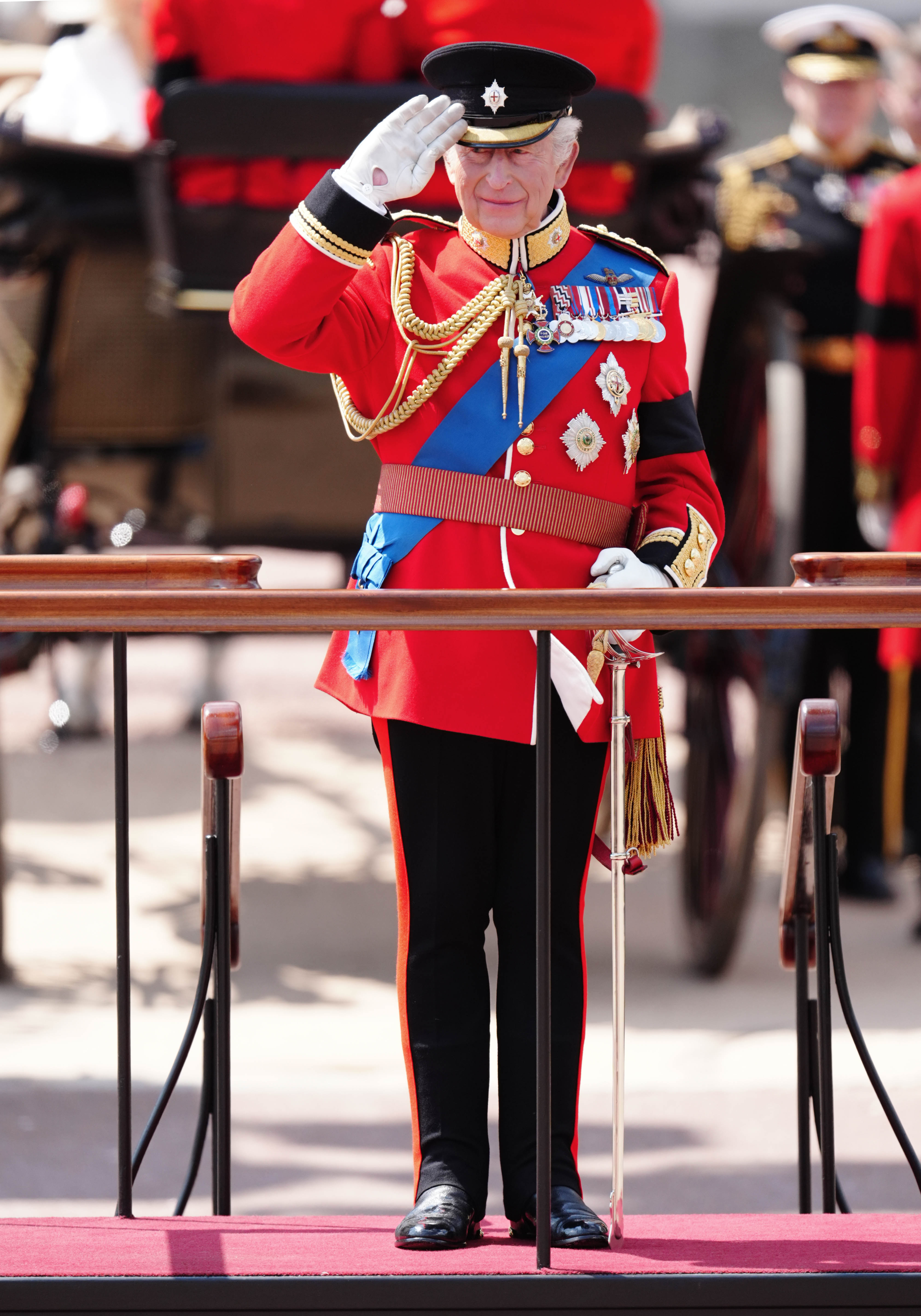 King Charles III gives a salute as he watches the parade march past after arriving back at Buckingham Palace after Trooping the Colour ceremony in central London | Source: Getty Images