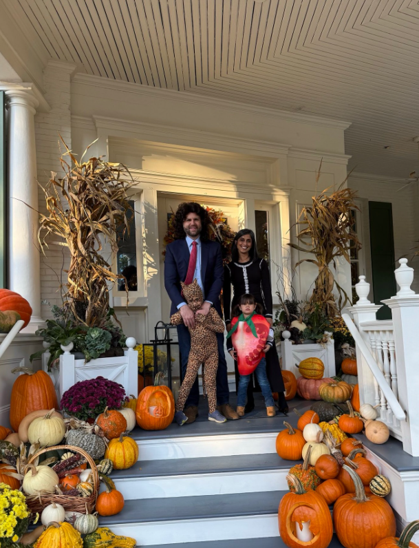 JD Vance and his wife, Usha, stand on the front steps of a house decorated with pumpkins, gourds, and autumn foliage, posing with their children in Halloween costumes. | Source: Instagram/vp