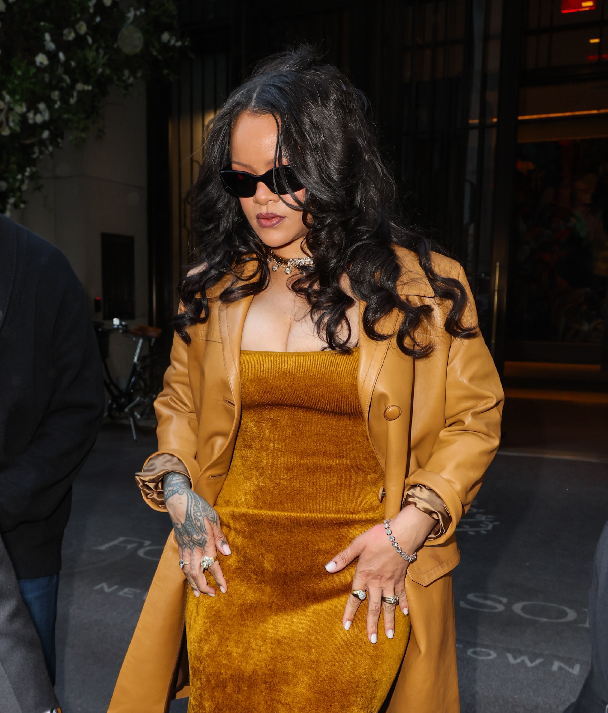 Rihanna is pictured in a brown ensemble, wearing sunglasses and layered jewelry during a public appearance. | Source: Getty Images