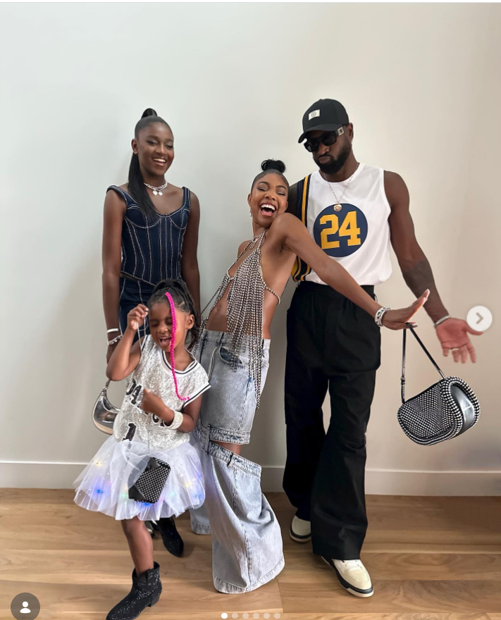 The family strikes a fun, fashion-forward pose indoors against a plain wall. Gabrielle stands in the center wearing a bold, stylish outfit with wide-leg pants, striking a playful pose. | Source: Instagram/gabunion