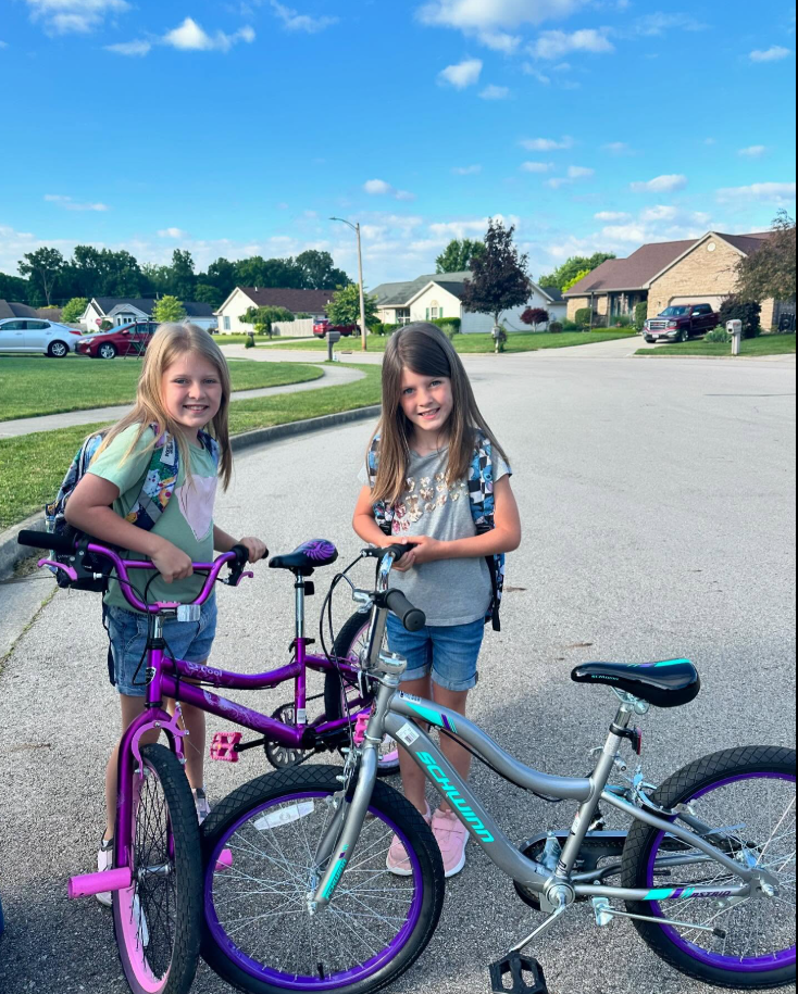 Caleb and Ashley Flynn's daughters are smiling at the camera while holding their bicycles. | Source: Facebook/AshleyFlynn