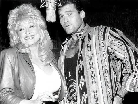 In the studio: Dolly Parton smiles as she shares a microphone with Billy Ray Cyrus during a recording session in this vintage black and white photograph. | Source: Facebook/BillyRayCyrus