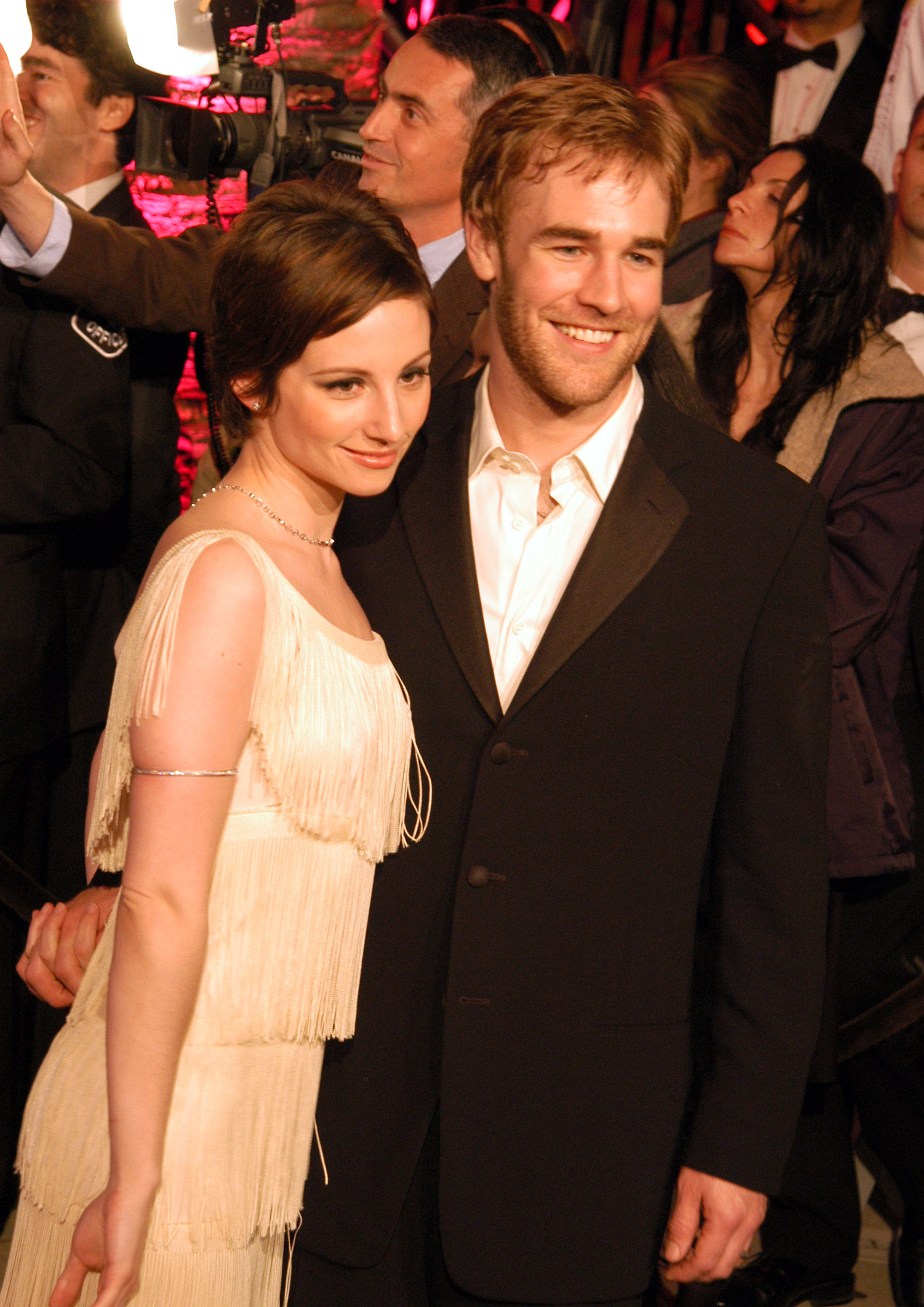 James Van Der Beek beams beside Heather McComb at the Vanity Fair Oscar Party. Her ivory fringe dress adds vintage glamour as she smiles serenely. Together, they exude effortless charm amid the Hollywood crowd.