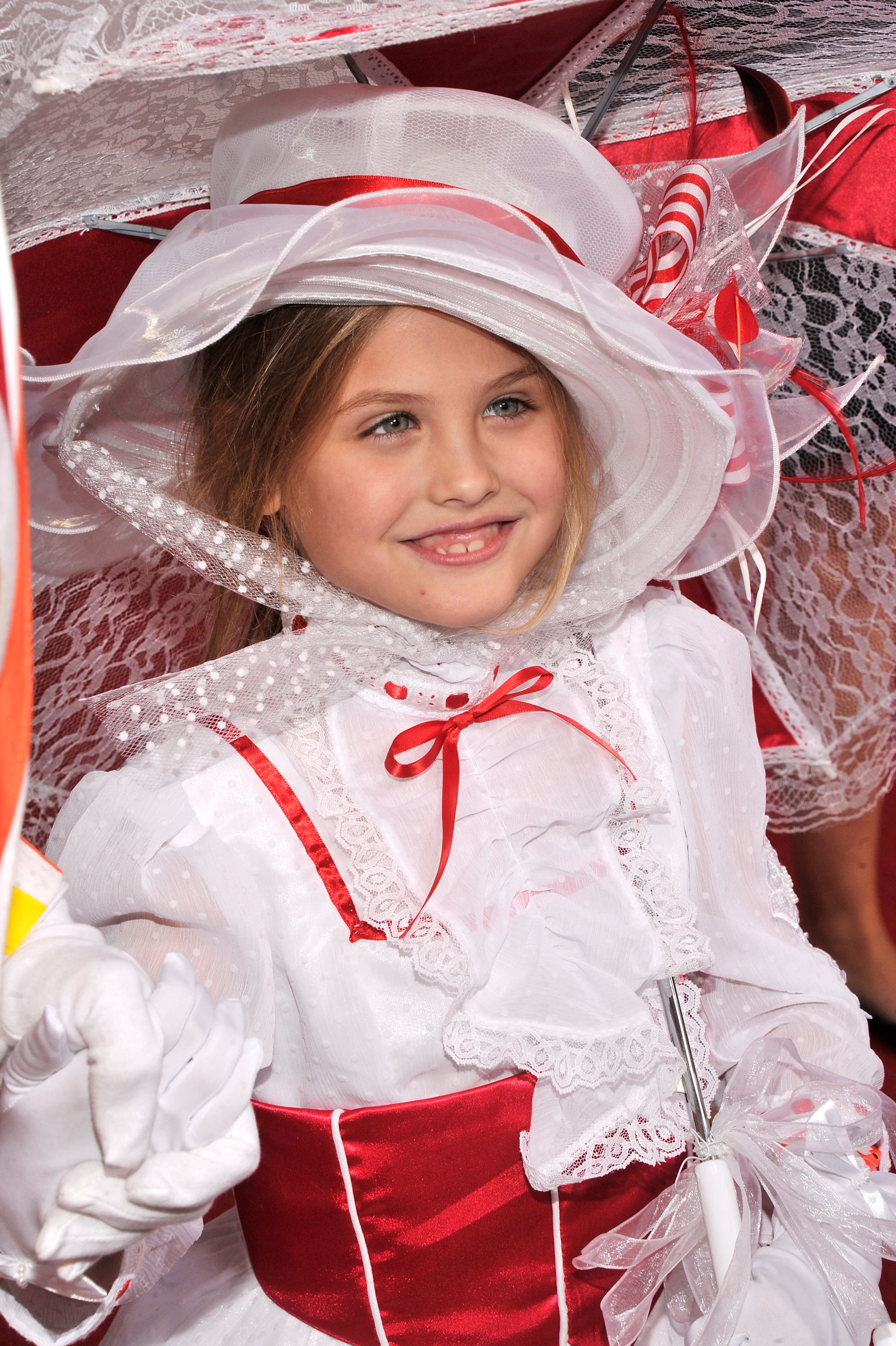 Framed by an elaborate white-and-red Derby hat and soft honey-brown hair, 6-year-old Dannielynn Birkhead smiled at the 139th Kentucky Derby at Churchill Downs in Louisville, Kentucky, on May 4, 2013. Her lace-trimmed white dress, glossy red sash, matching ribbons, and dainty gloves created a wonderfully theatrical look, while her bright blue eyes and sweet grin gave the grand ensemble a playful, youthful charm.