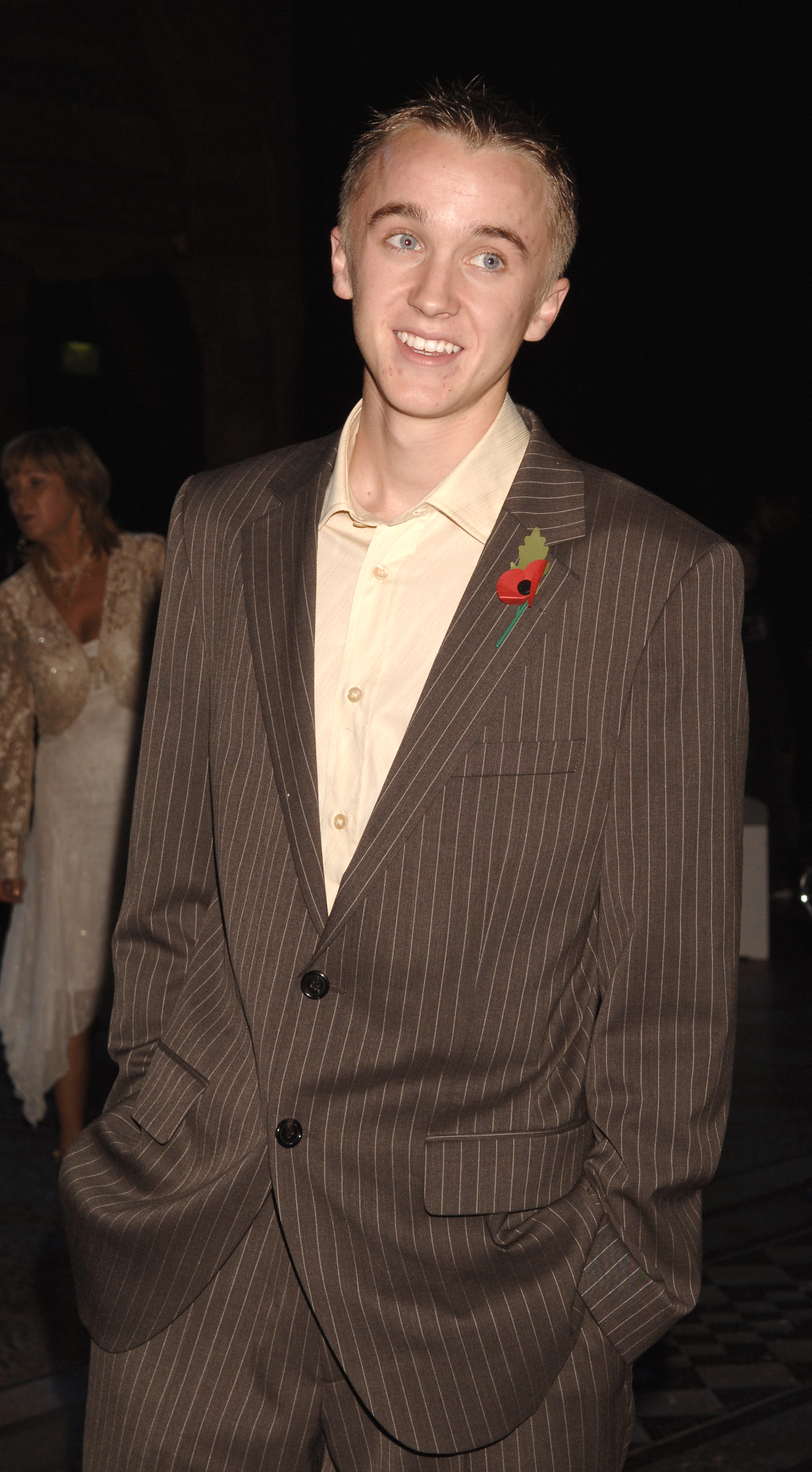 Tom Felton arrives at the "Harry Potter and the Goblet of Fire" aftershow party looking polished in a pinstripe suit and soft yellow shirt. A bright poppy pin adds a thoughtful touch to his youthful, easy going charm. With a relaxed smile and hands in his pockets, he exudes the quiet confidence of a rising star enjoying the night.
