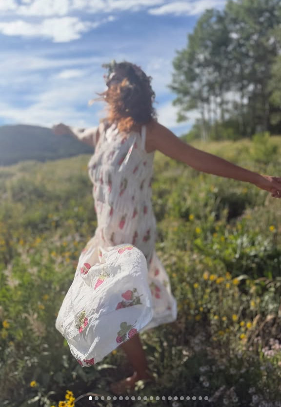 Judd stretches out her arms in a field of wildflowers, wearing a flowing white floral dress. The carefree outdoor photograph offers a different view of the actress from the close-up selfies and public appearances that have drawn attention to her facial features. | Source: Instagram/ashley_judd