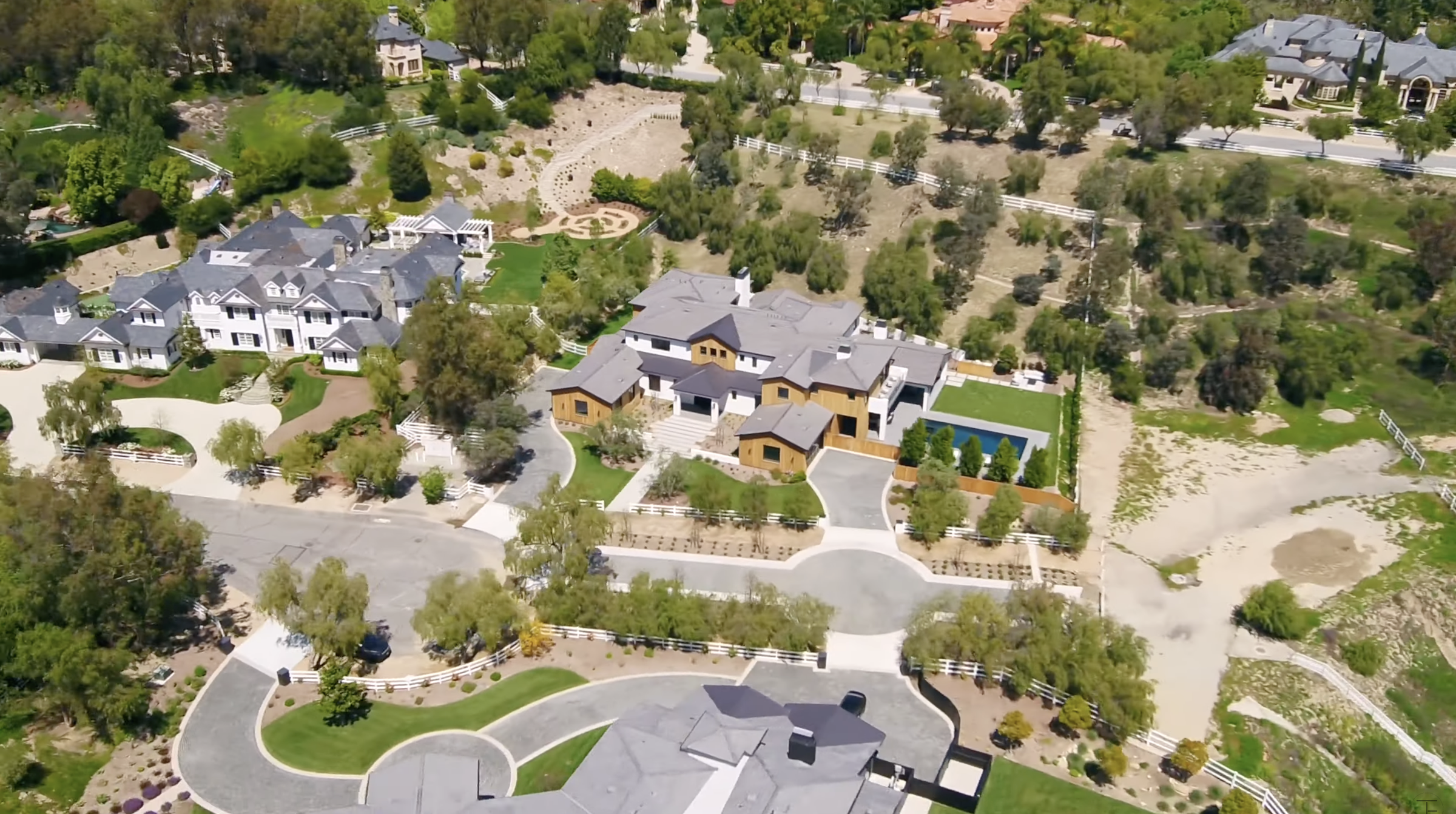 An aerial view puts the Hidden Hills property's size into perspective, with the residence surrounded by neighboring estates, mature trees and open land. The pool can be seen tucked along one side of the house. | Source: Youtube/Tomer.Fridman