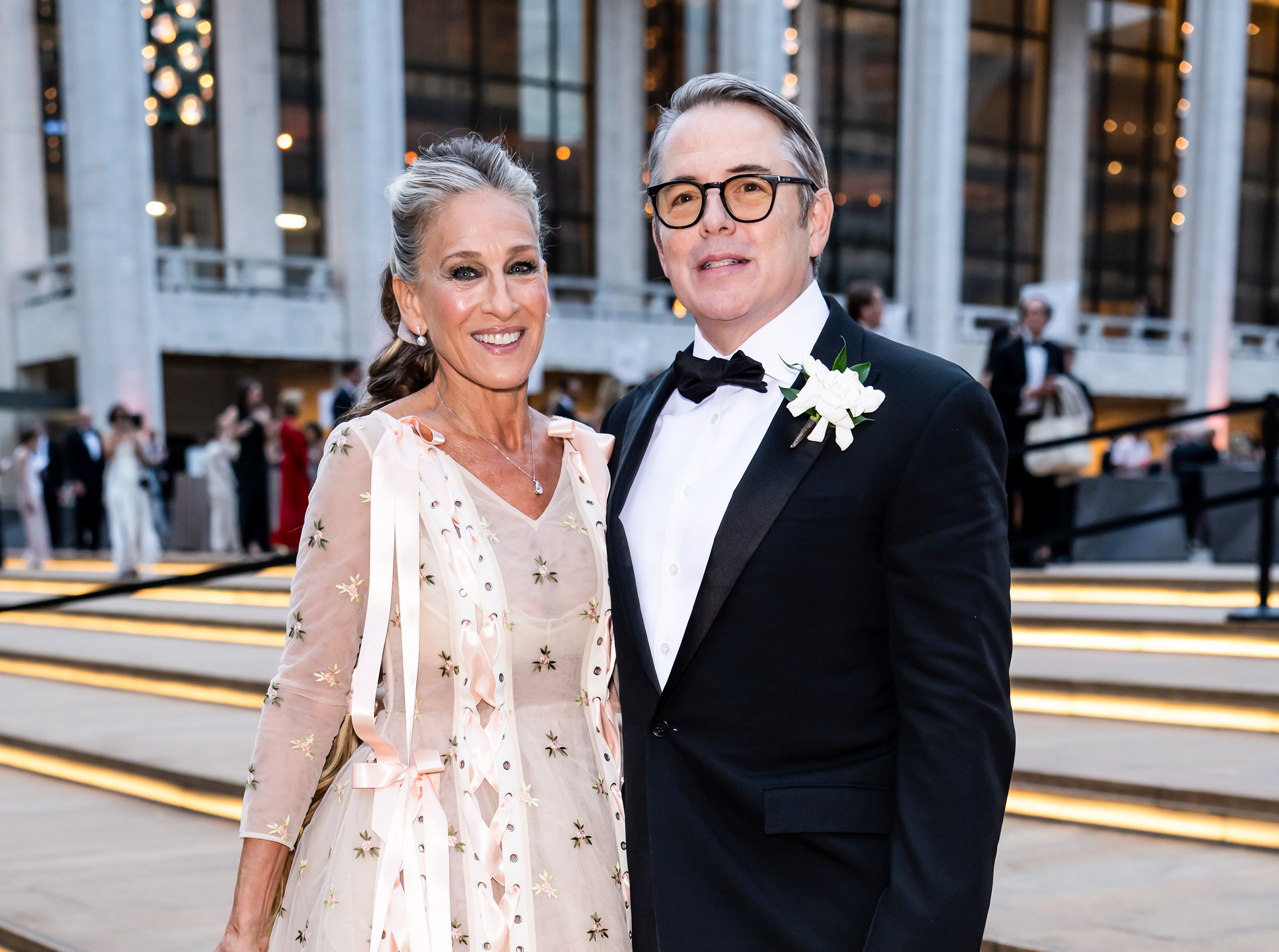 Parker poses with her husband, Matthew Broderick, outside Lincoln Center in New York City. The actress wears a delicate floral dress, with her gray roots swept back from her face.