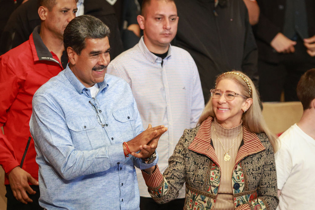 Venezuelan President Nicolas Maduro with his wife and primera combatiente Cilia Flores greets the audience during the presentation of a biographical film and a book about him at the Teresa Carreño Theater on July 14, 2024 in Caracas, Venezuela. | Source: Getty Images