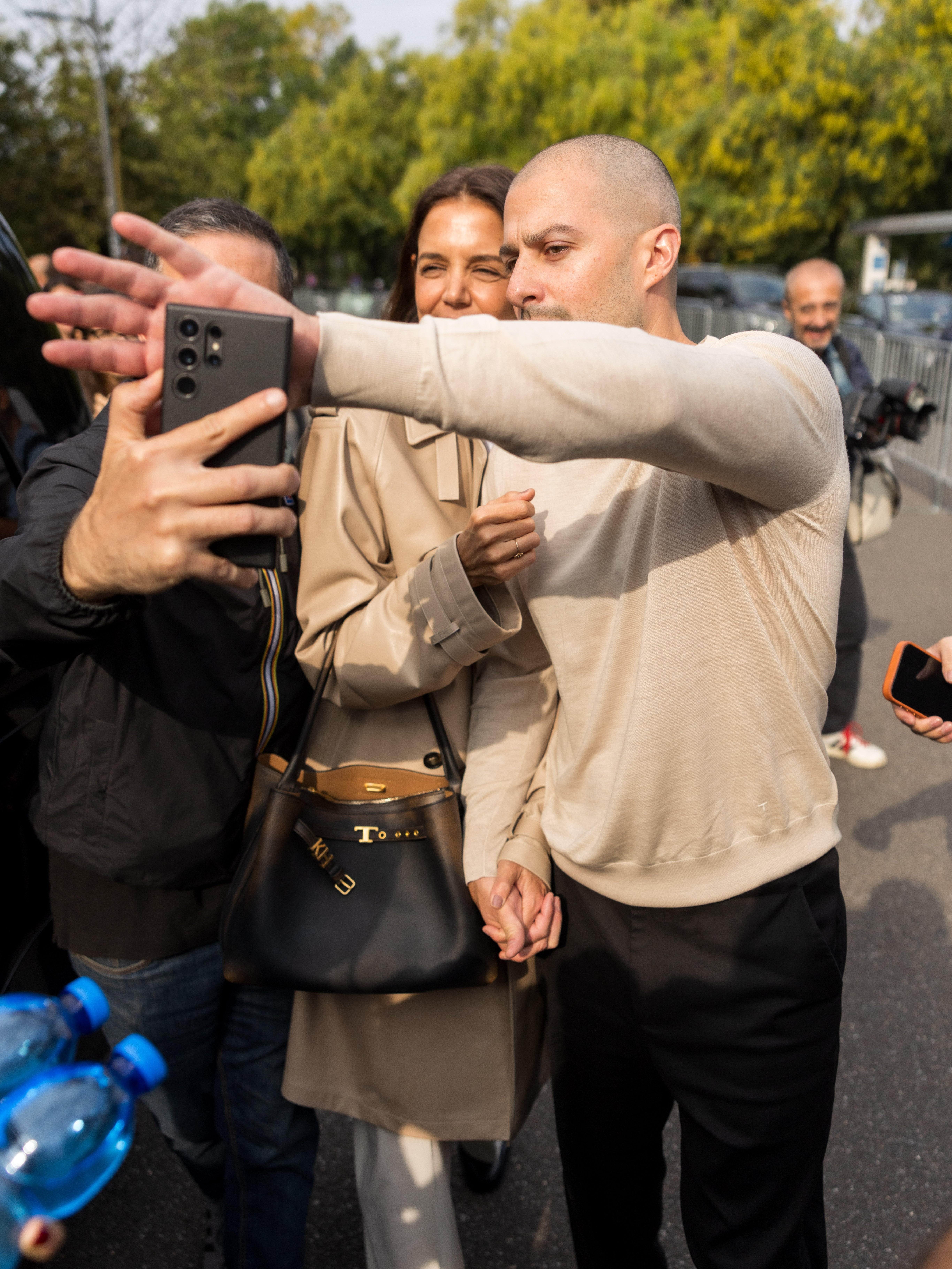 A passerby stretched out a smartphone to snap a quick selfie as the couple made their way through the bustling crowd outside the show venue. Katie remained composed and kept a tight grip on Jason’s hand, carrying her personalized "KH" monogrammed leather bag as photographers and onlookers surrounded them in the Italian sun. | Source: Getty Images