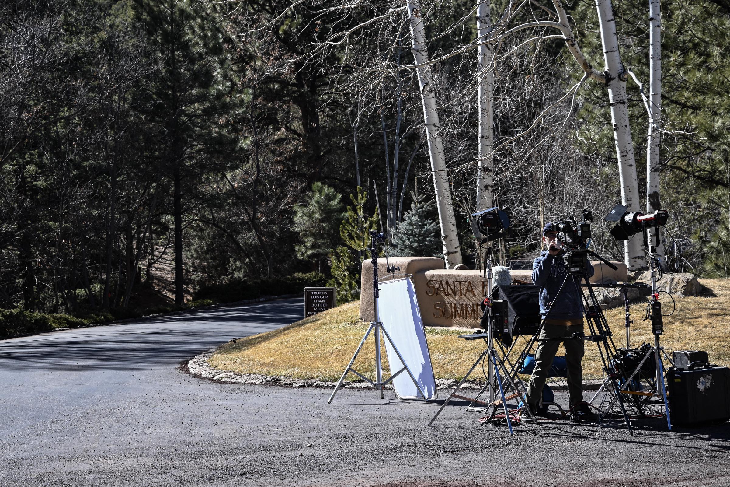 A reporter sets up cameras at the entrance to the Santa Fe Summit neighborhood where Gene Hackman lived on February 28, 2025 | Source: Getty Images