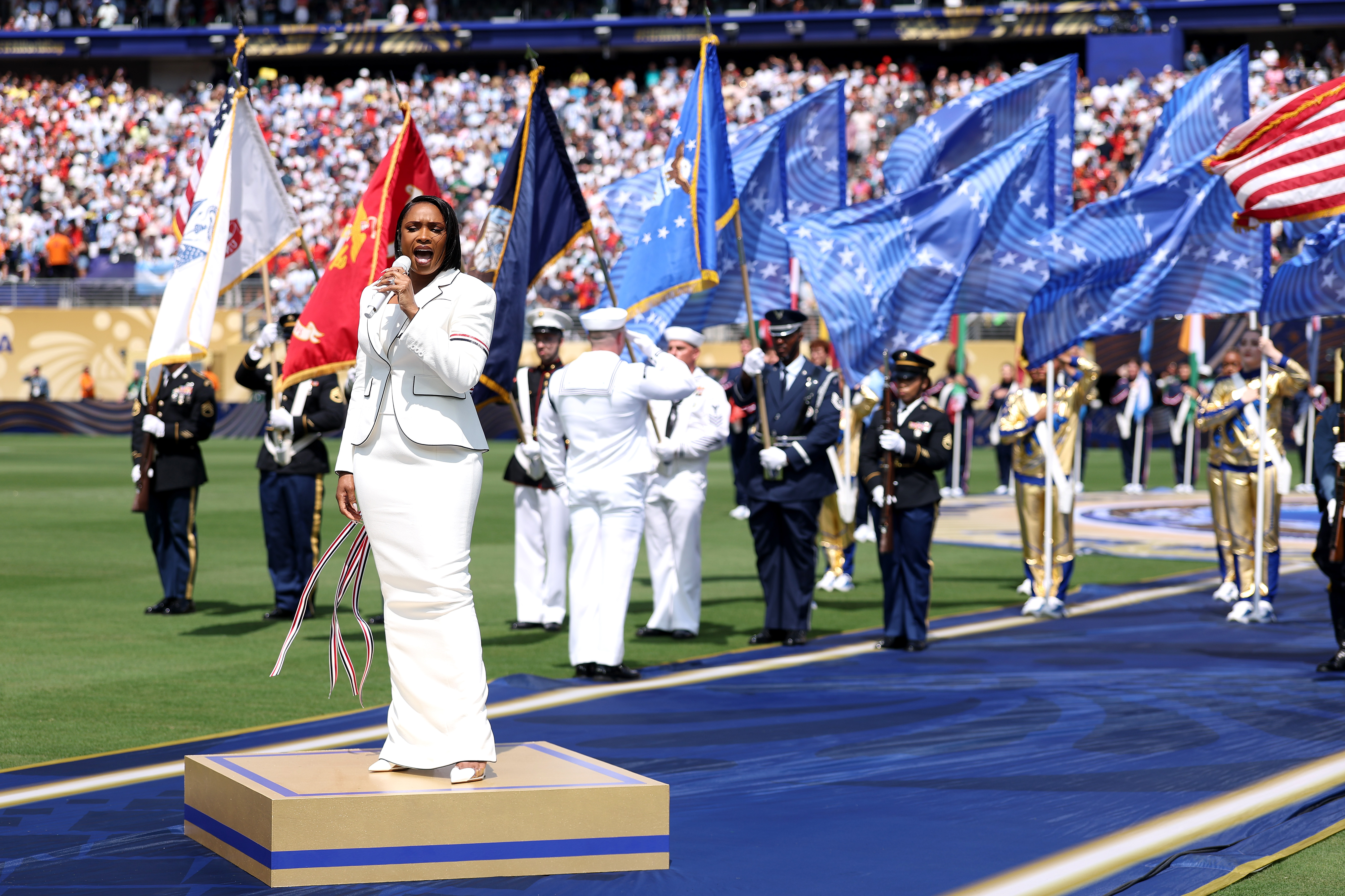 Hudson's performance formed part of a carefully staged pre-match tribute involving uniformed personnel and national symbols. Despite the scale of the presentation, the online conversation quickly narrowed to one question: was the arrangement stirring or simply too much? | Source: Getty Images