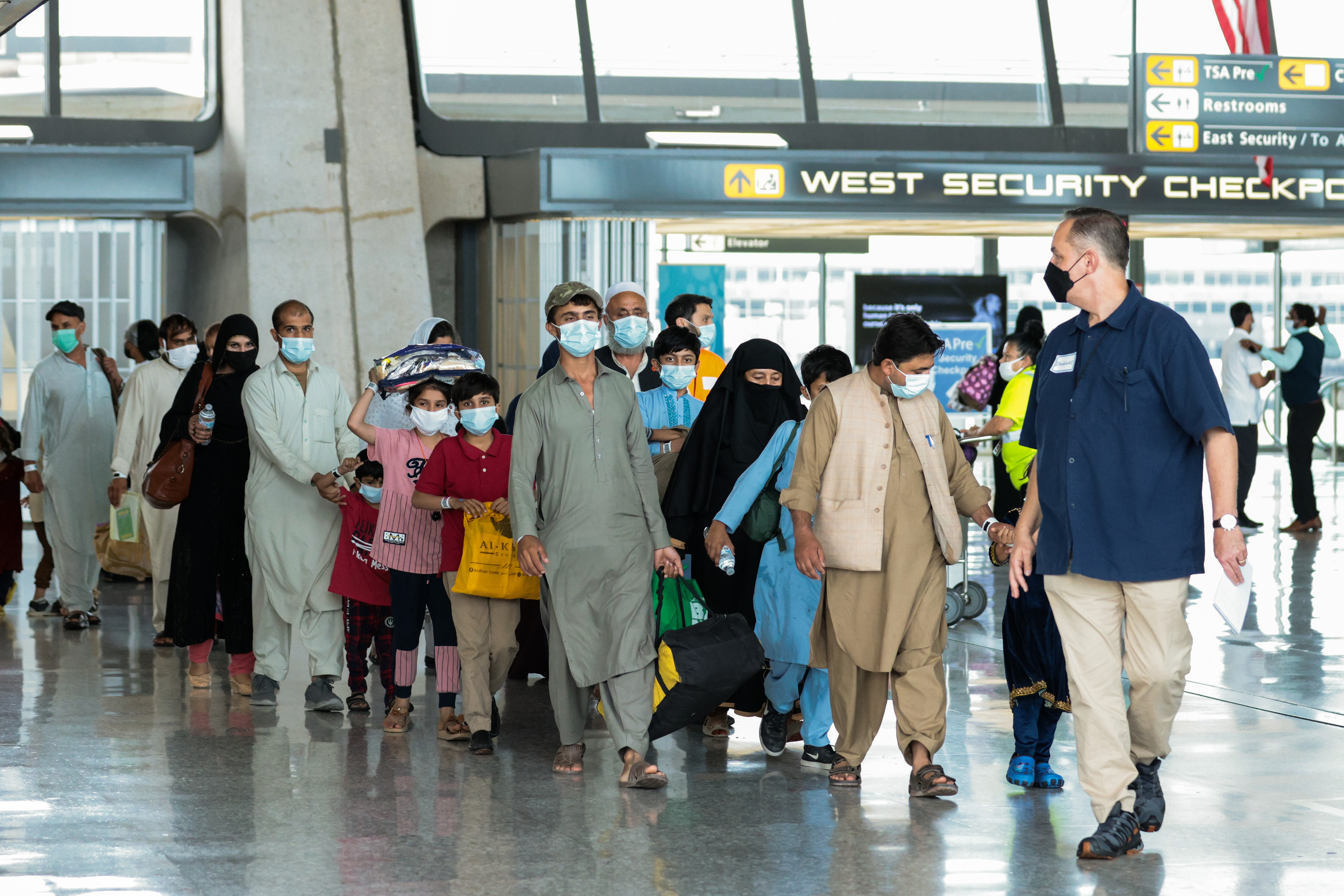 Refugees walk through the departure terminal to a bus at Dulles International Airport after being evacuated from Kabul following the Taliban takeover of Afghanistan on August 31, 2021 in Dulles, Virginia | Source: Getty Images