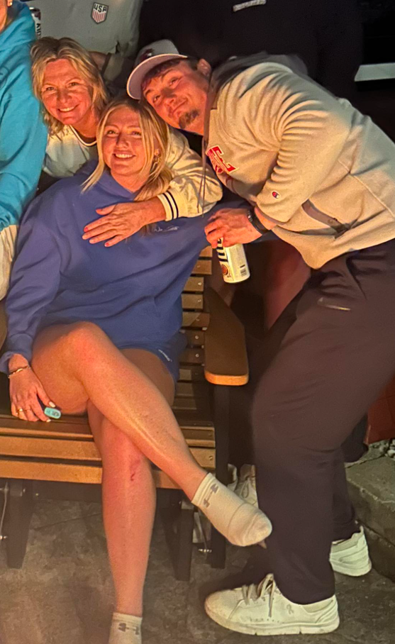 By a firelit evening, Jack Pugh leans in with two women on a bench — faces glowing in warm light, the mood relaxed and quietly intimate. | Source: Facebook/KennaLynMcClelland