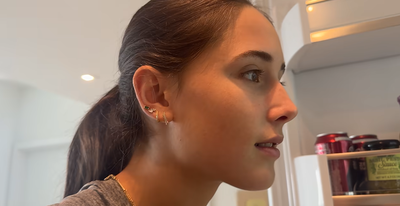 Kai Trump's friend, Emma, looks inside her refrigerator while filming a vlog about her illness. Emma selected easy-to-prepare foods, including pasta, bread, and fruit, to help her while she recovered. | Source: Youtube/kaitrump