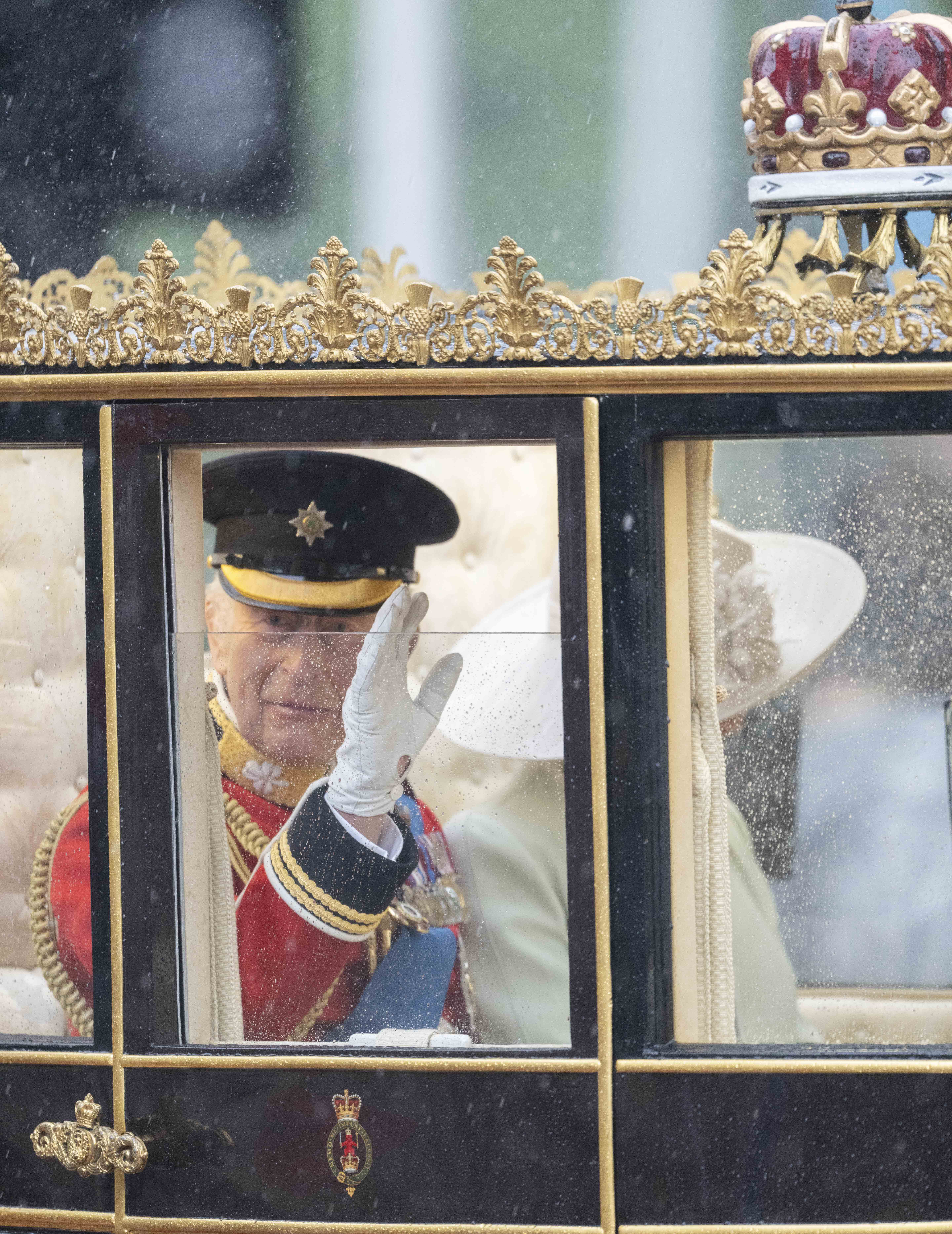 Through rain-specked glass, King Charles III acknowledges onlookers during the Trooping the Colour procession on June 15, 2024 | Source: Getty Images
