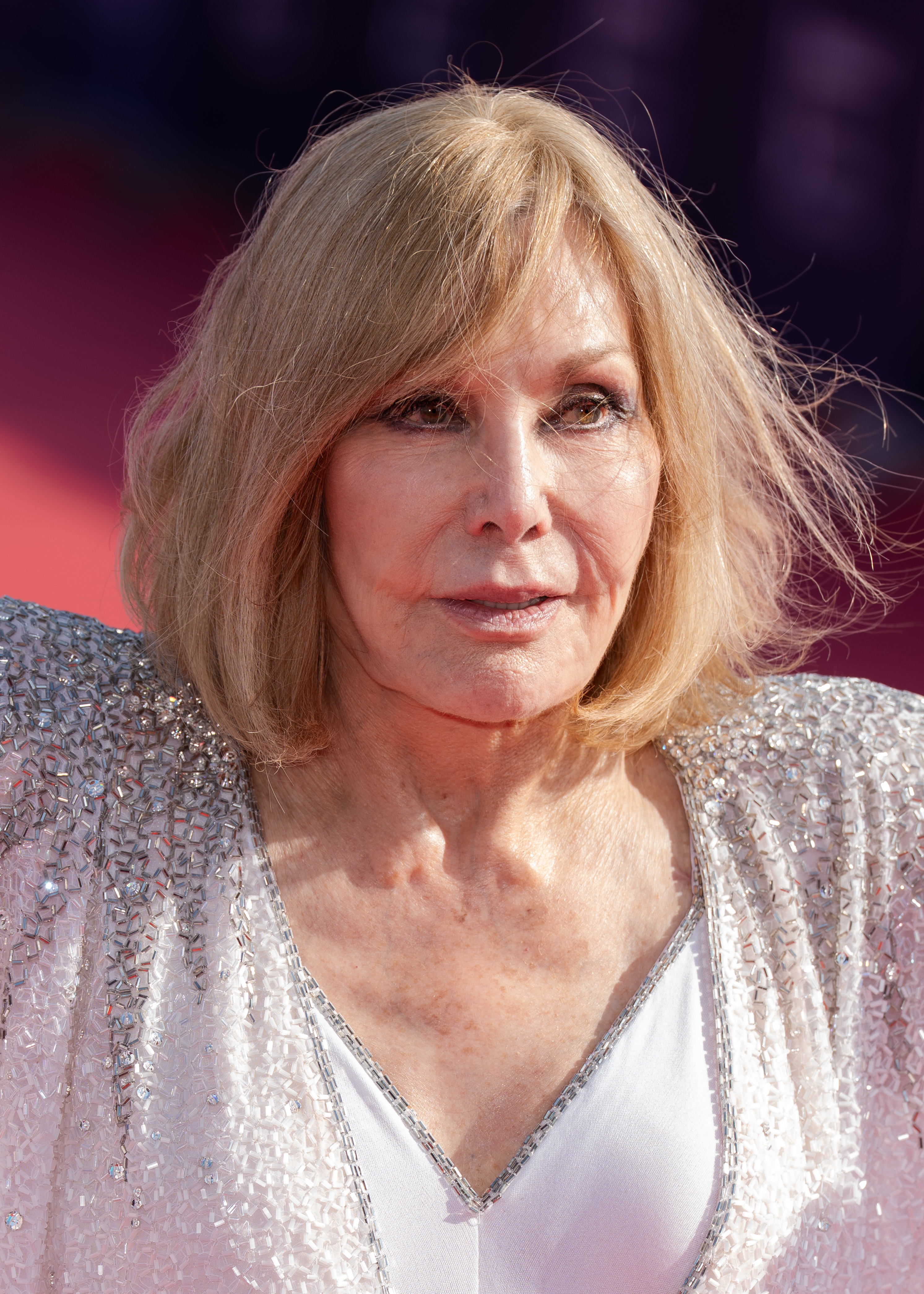 Kim Novak arrives at the 51st Deauville American Film Festival on September 6, 2025, wearing a black-and-white sheer wrap over a dark outfit. She walks beside another woman outside the venue in the daylight. | Source: Getty Images