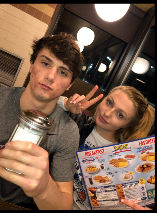 At a diner table, Jack Pugh holds a shaker while Kenna Lyn McClelland flashes a peace sign over a menu — simple, slightly tired, but quietly content. | Source: Facebook/KennaLynMcClelland