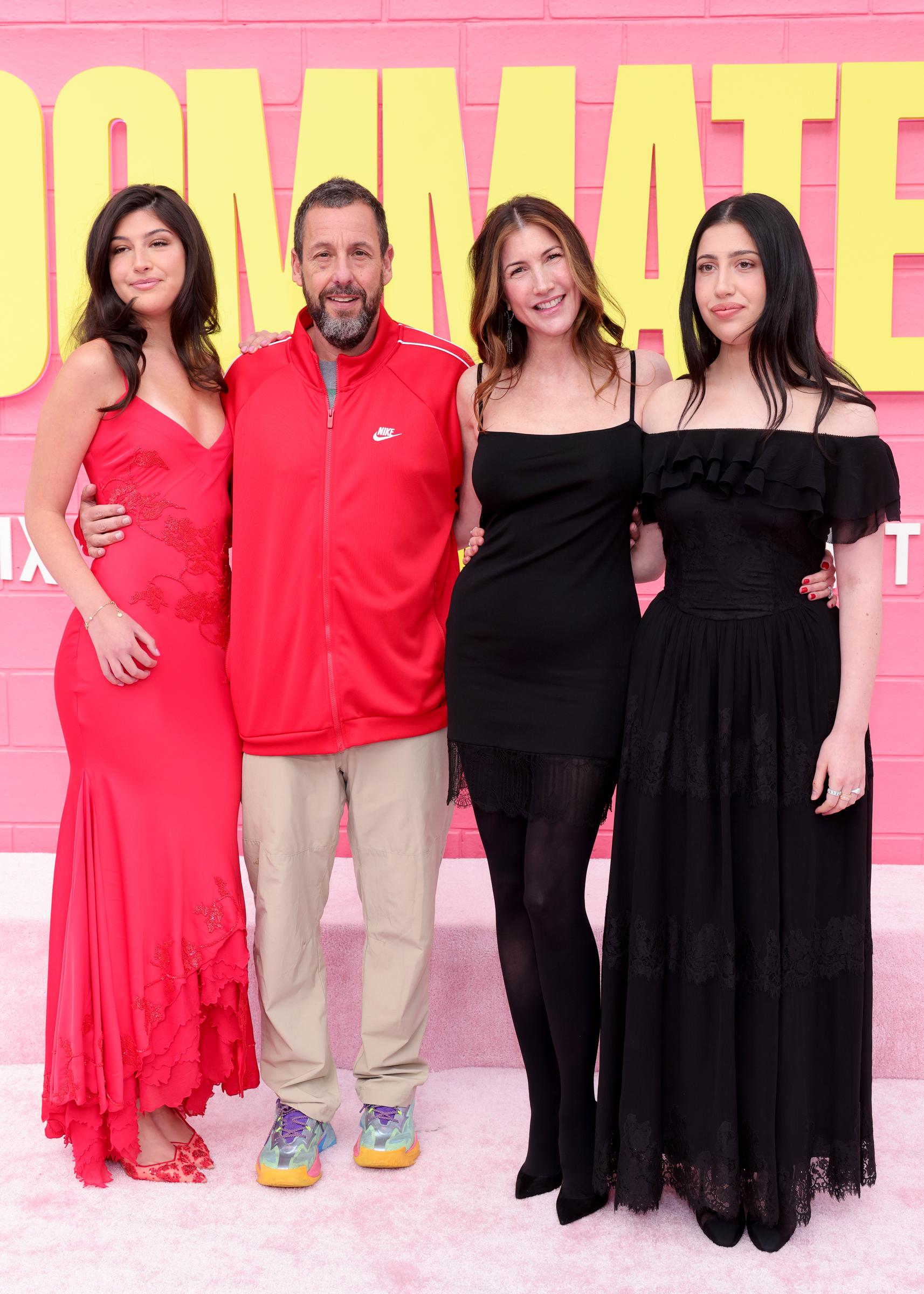 Sunny Sandler, Adam Sandler, Jackie Sandler, and Sadie Sandler blend polished glamour with relaxed style at the premiere. Sunny stuns in a red lace gown, Sadie wears an off-shoulder black dress, while Adam’s sporty look contrasts Jackie’s sleek black mini.