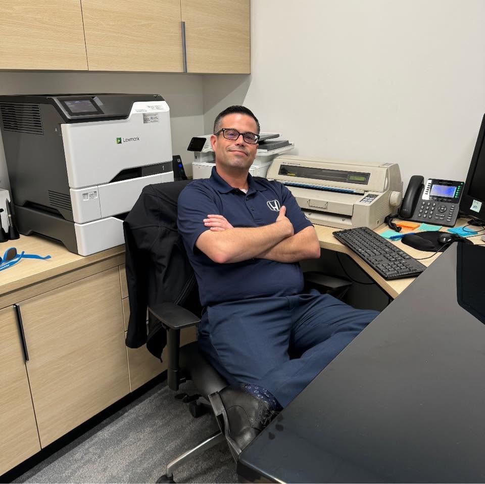 The former child star sits at his desk in a Honda dealership office, wearing a navy polo shirt and smiling at the camera — a glimpse of his life away from Hollywood. | Source: Facebook.