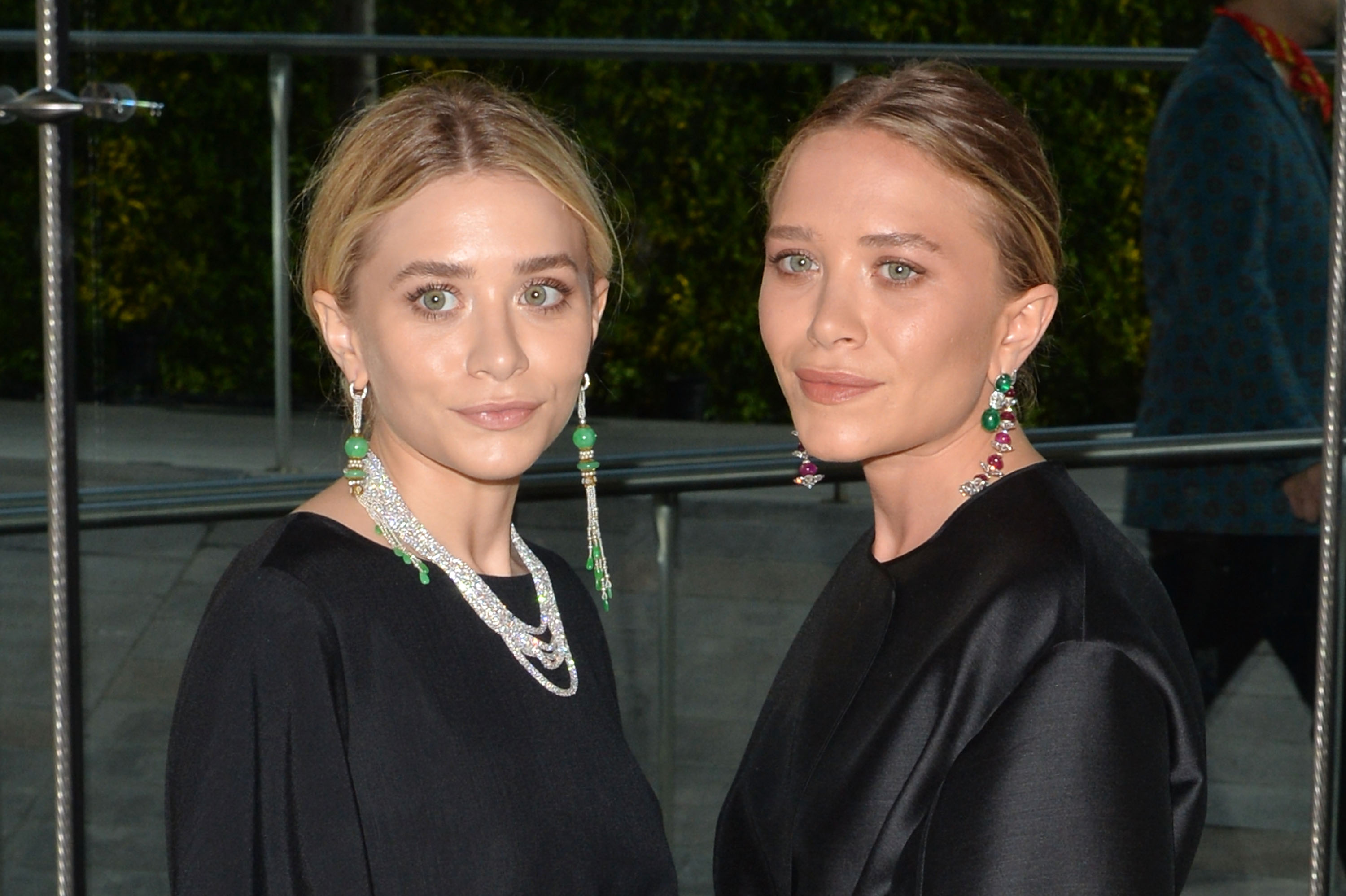 Minimalist elegance and serene, composed facial expressions defined 28-year-old Mary-Kate and Ashley Olsen at the June 2, 2014 CFDA Fashion Awards, where sleek, center-parted updos highlighted their sharp cheekbones and minimalist black ensembles accessorized with striking diamond and gemstone jewelry.