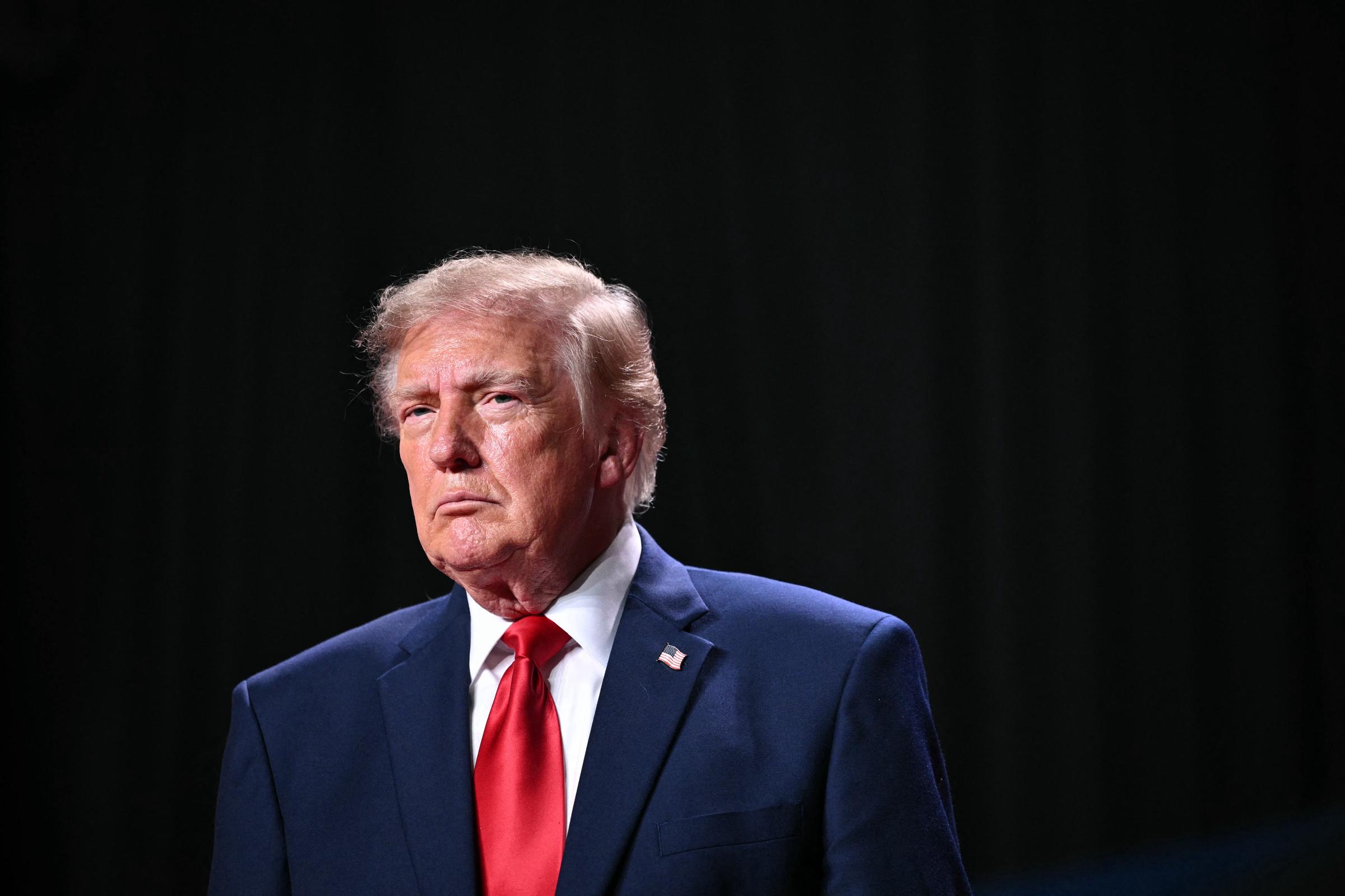 Donald Trump poses in a navy suit and purple tie as he announces his latest press secretary appointment, praising her campaign work and expressing confidence in her ability to communicate his administration’s agenda. | Source: Getty Images