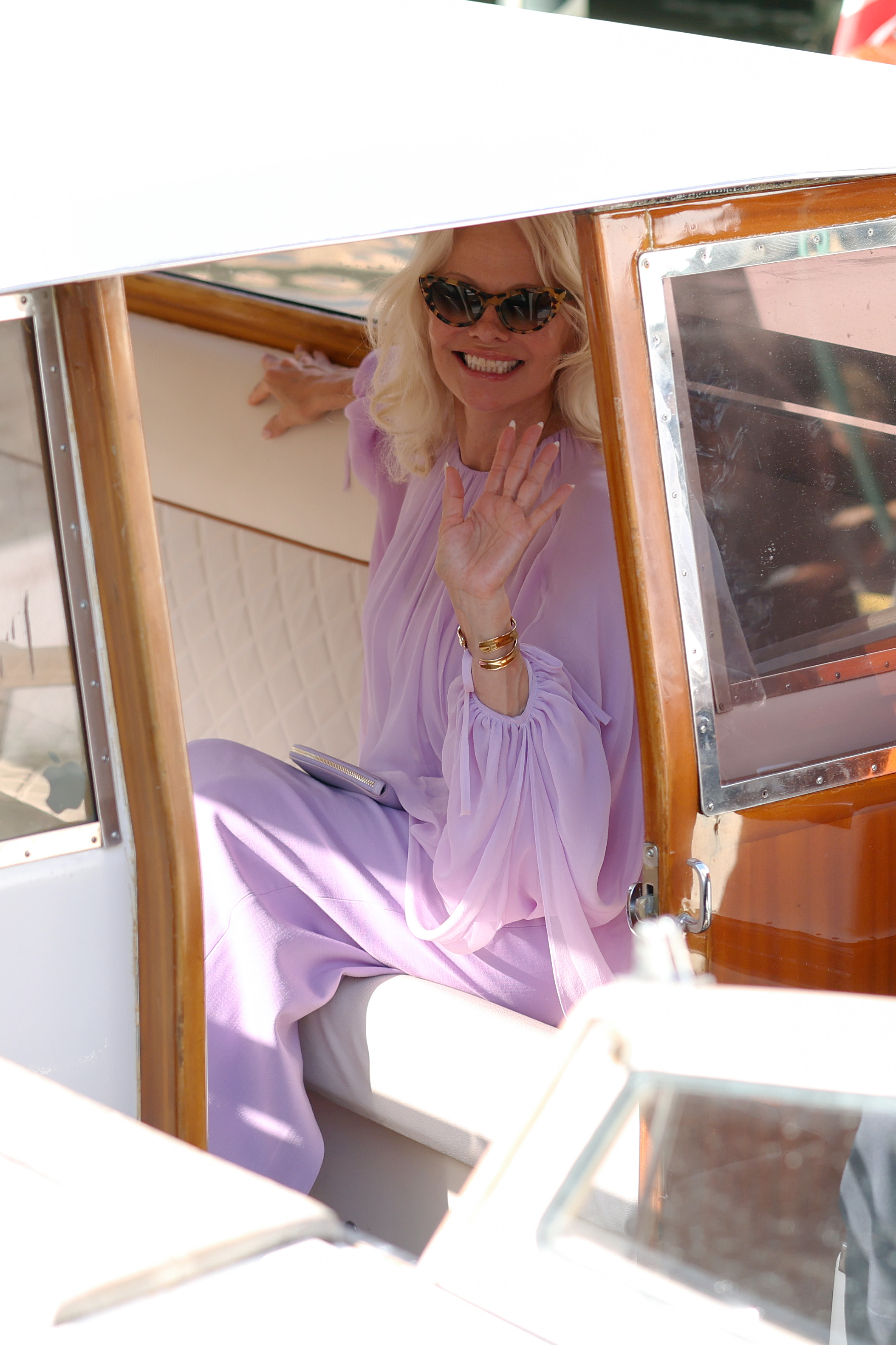 Anderson waved from a boat as she arrived at the Hotel Excelsior Venice Lido Pier during the festival. Her lavender ensemble continued the softer style she chose for her appearances in Venice that day. | Source: Getty Images