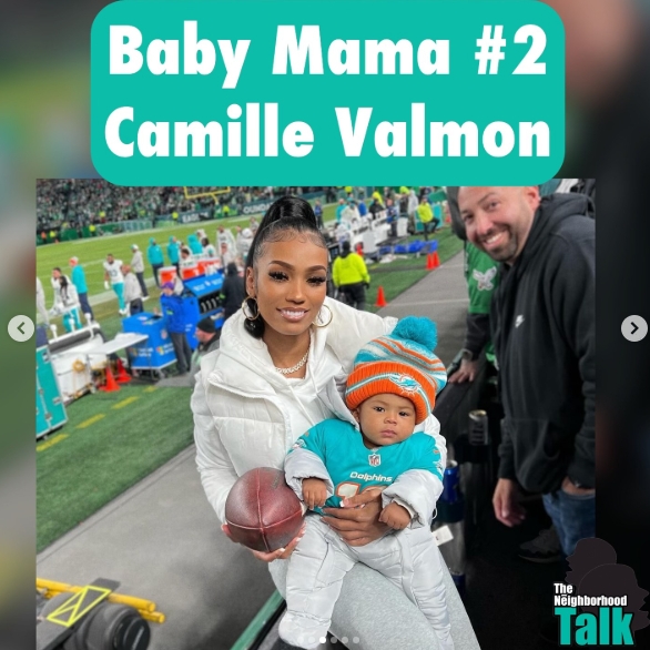 Camille Valmon holds her infant son, Tyreek D'Shaun Hill Jr., while standing near the field at a Miami Dolphins game. The youngster is dressed for the occasion in Dolphins gear and a colorful winter hat, while his mother holds a football in her other hand. Valmon has shared several glimpses of Hill spending time with their son on social media. | Source: Instagram/theneighborhoodtalk