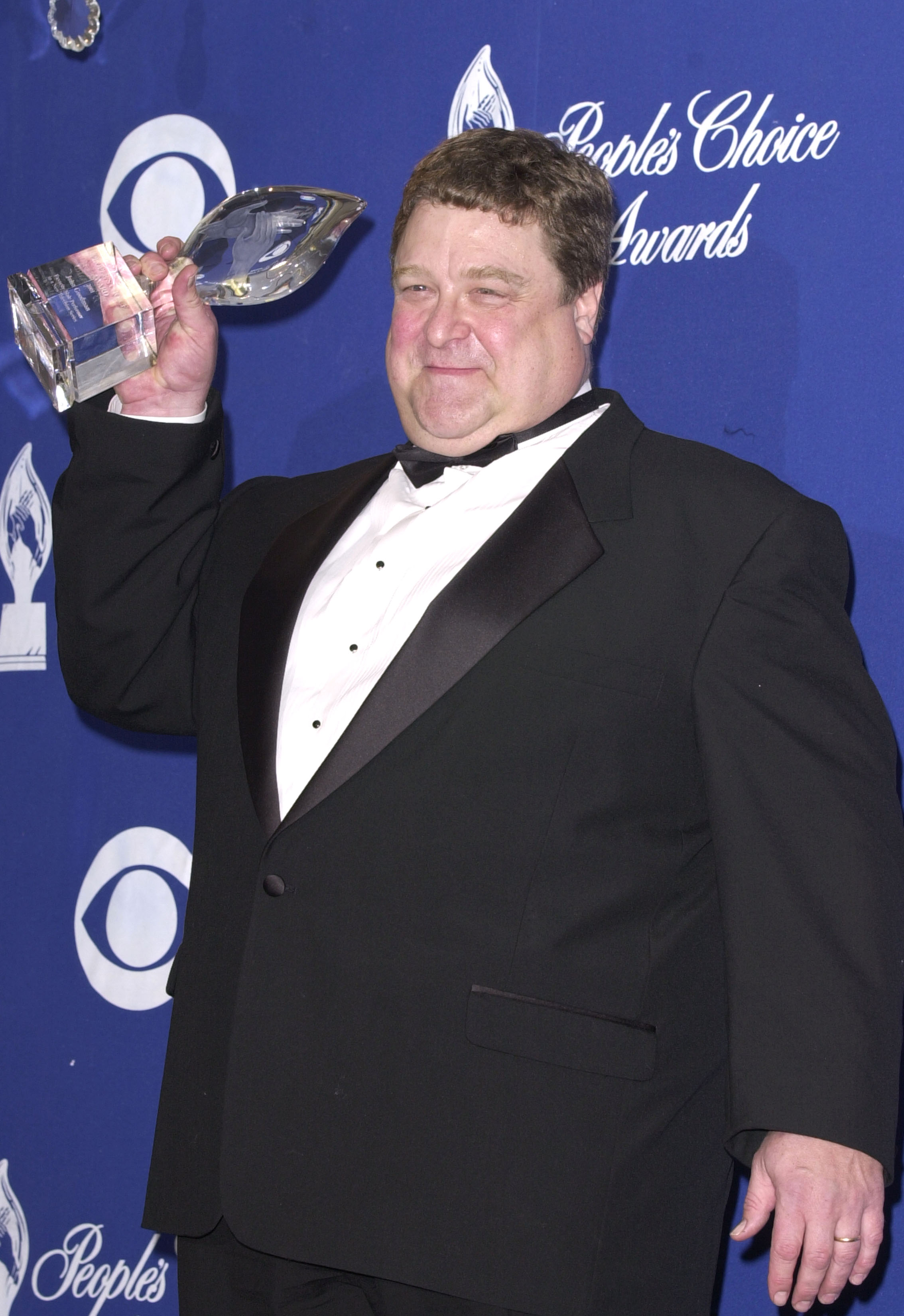 Dressed in a white shirt with black buttons tucked into a black suit and a big smile on his face, Goodman was photographed with an award during the 27th Annual People's Choice Awards at Pasadena Civic Auditorium in Pasadena, California.