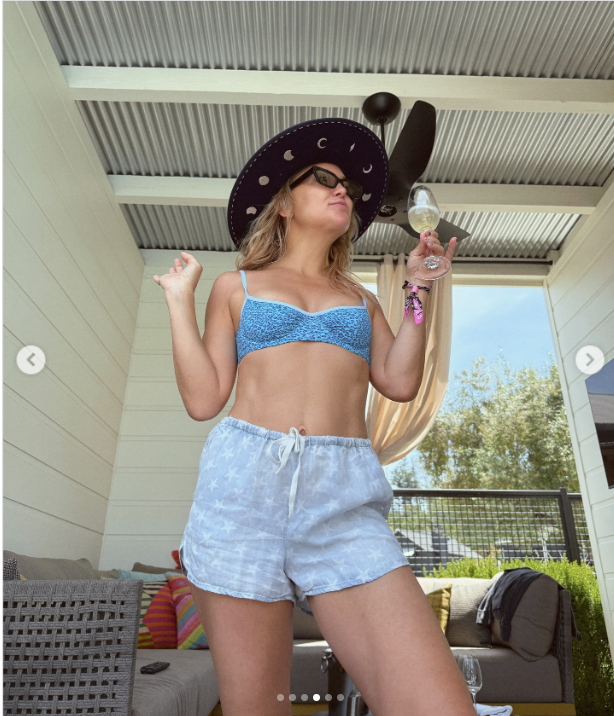 Kate Hudson struck a confident pose in a blue bikini top, star-print shorts, and a wide-brimmed hat while holding an almost-empty wine glass during her BottleRock weekend. The relaxed cabana setting and her carefree vibe reflected the fun and festive spirit of her Napa escape | Source: Instagram/katehudson